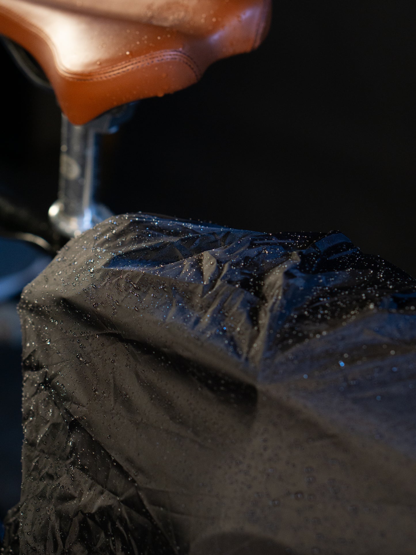 Wasserdichte Regenhülle in Schwarz von Spleen Berlin mit Wassertropfen.