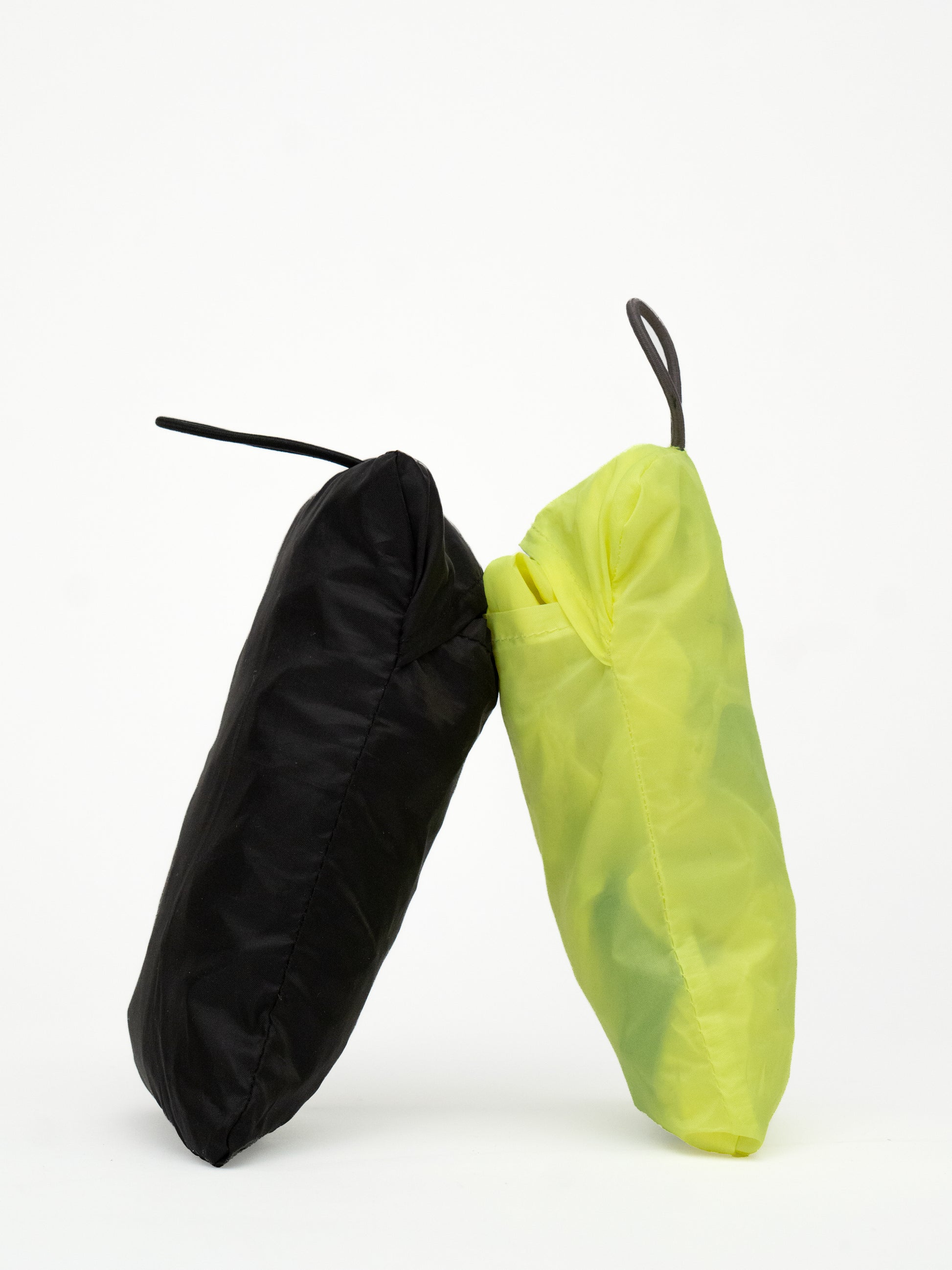 Zwei verpackte wasserdichte Regenhuellen in schwarz und neongelb von Spleen Berlin an einander gelehnt
