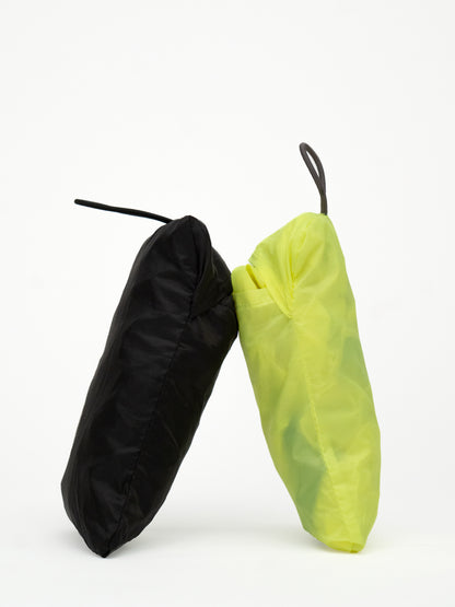 Zwei verpackte wasserdichte Regenhuellen in schwarz und neongelb von Spleen Berlin an einander gelehnt