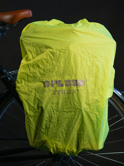 Neongelber wasserdichter Regenschutz von Spleen Berlin für Fahrradrucksäcke  mit 30l Volumen am Fahrrad befestigt bei Nacht.